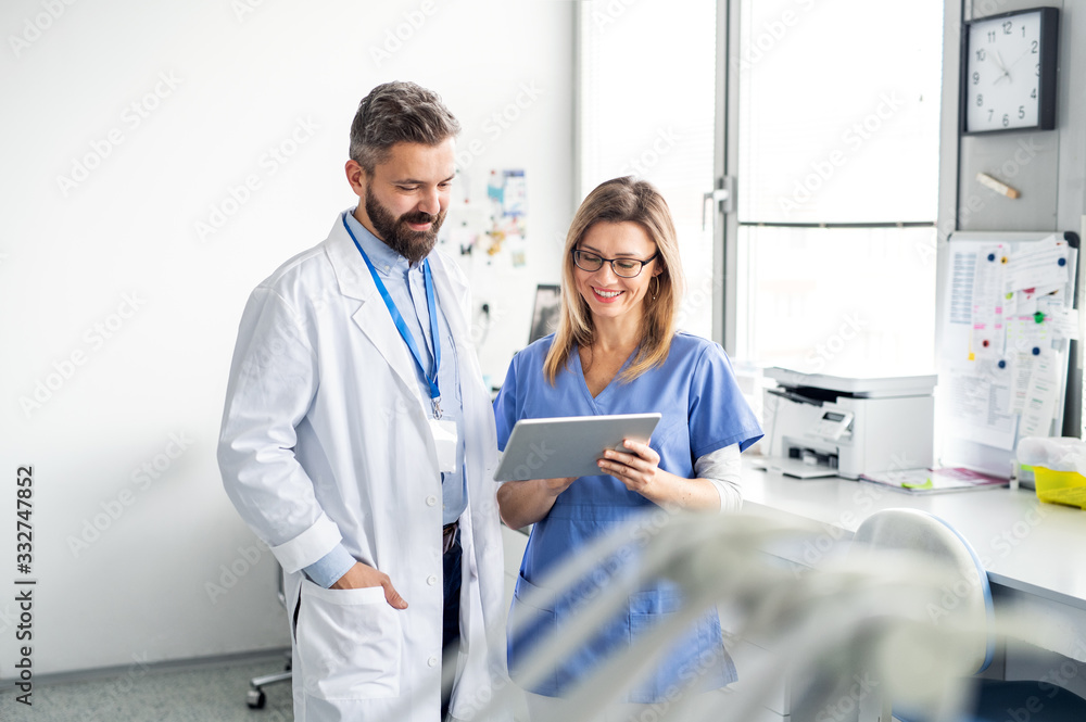 Fototapeta premium A dentist with dental assistant in modern dental surgery, working.