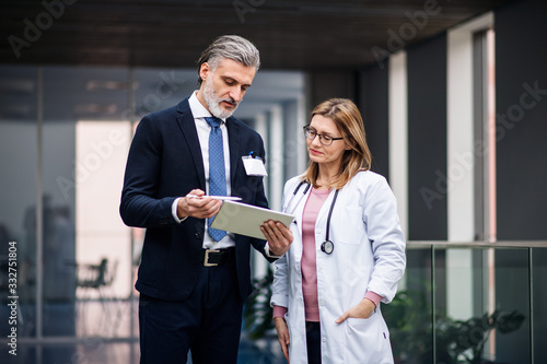 Pharmaceutical sales representative with tablet talking to doctor. photo