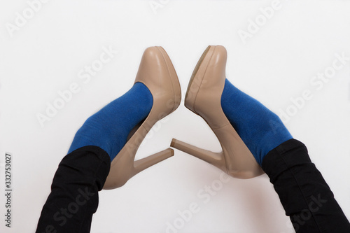 legs of a girl in blue socks, black pants, nude high-heeled shoes. Legs stick up