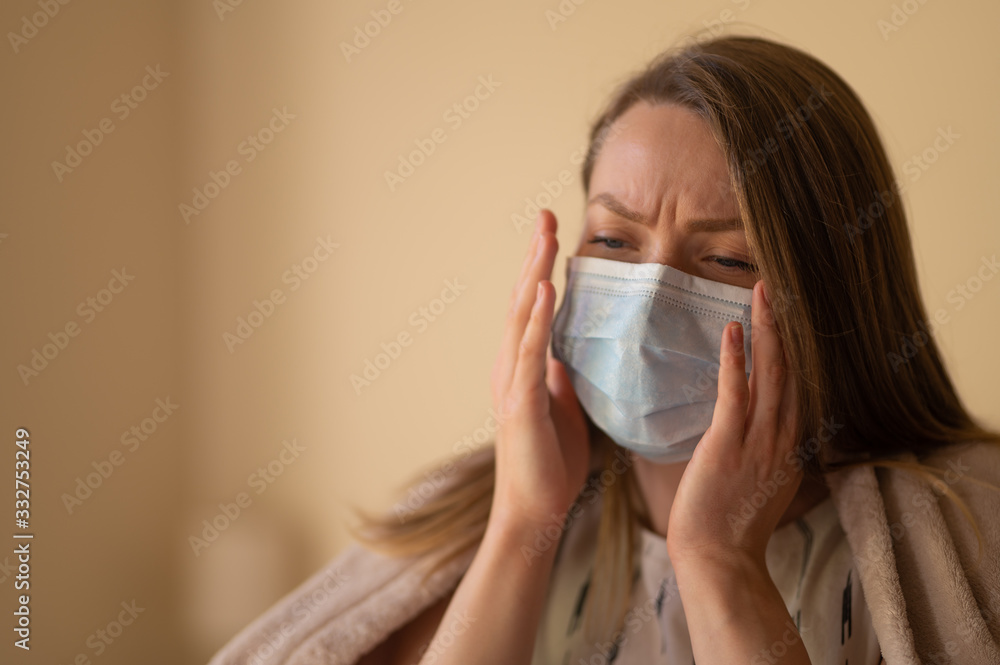 Girl in a mask and temperature with a coronavirus. Symptoms of temperature, covered with a blanket, in the room Girl in a mask and temperature with a coronavirus. Symptoms of temperature, covered with a blanket, in the room
