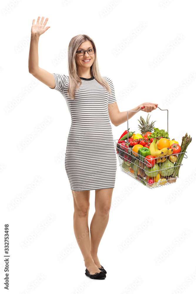 Young woman with a shopping basket with fruits and vegetables waving Young woman with a shopping basket with fruits and vegetables waving