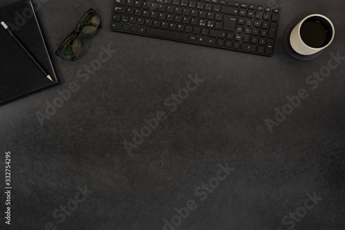 Top view of black concrete office desk with computer and supplies