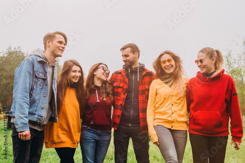Funny selfie with friends. company of cheerful friends making selfie and smiling while standing outdoors. people wear red and yellow jumpers. young people resting in nature, talking and laughing