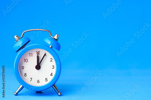 Alarm clock on a blue background, on the right is an empty place