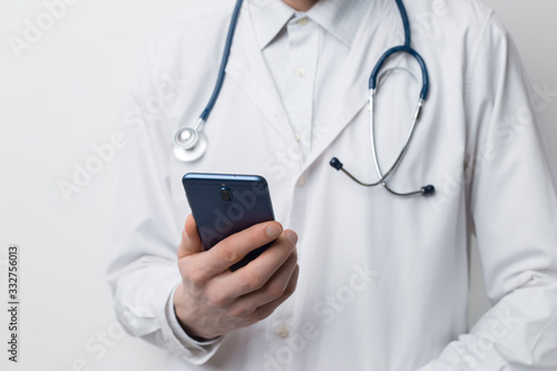Doctor holds a mobile phone in his hand for online patient consultation.