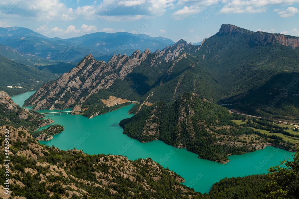 Landscape of a turquoise pond in the middle of a green valley