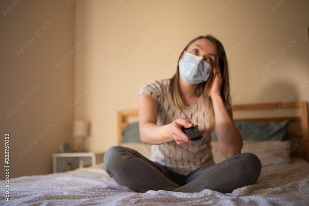 A girl in quarantine with a mask watches TV. Rest in quarantine and keeping it at home. Coronavirus and the danger from it A girl in quarantine with a mask watches TV. Rest in quarantine and keeping it at home. Coronavirus and the danger from it