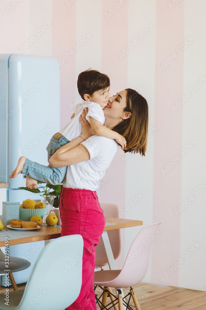 Mother holding on hands cute little son on the kitchen. Mother holding on hands cute little son on the kitchen.