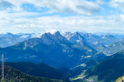 A distant view on the snowy slopes of Austrian Alps. There is a massive mountain chain in the back, partially covered with snow. Early spring coming to the Alps. Overcast. Achievement and fun.