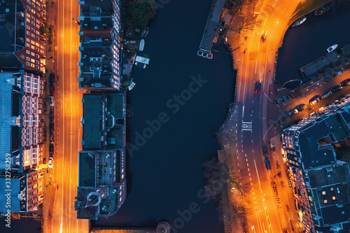 Amsterdam canal, old dancing houses, river Amstel and illuminated streets, aerial top view at night, drone photo.