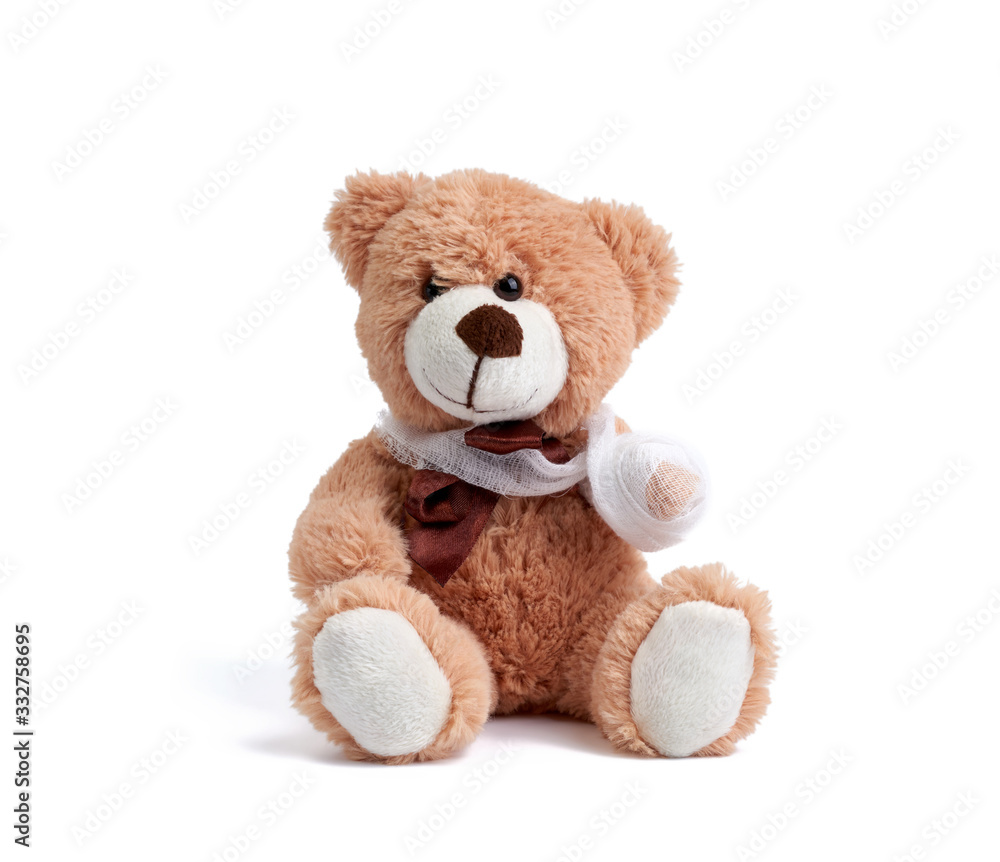 funny vintage brown curly teddy bear with rewound paw with white gauze bandage isolated on white background