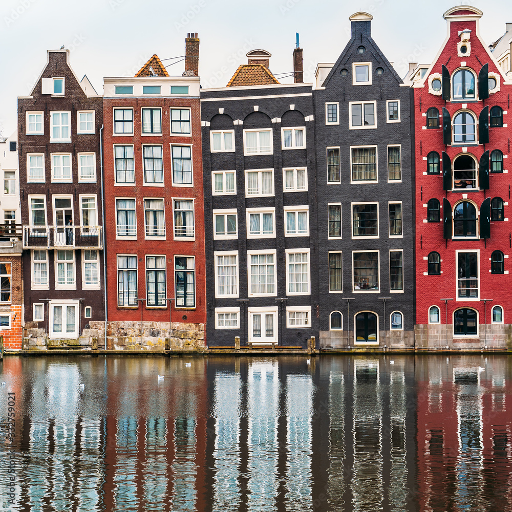 Famous dancing houses and buildings in Amsterdam with reflection in canal water.