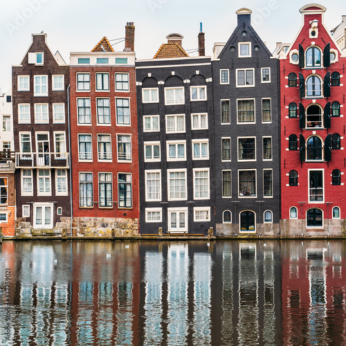 Famous dancing houses and buildings in Amsterdam with reflection in canal water.