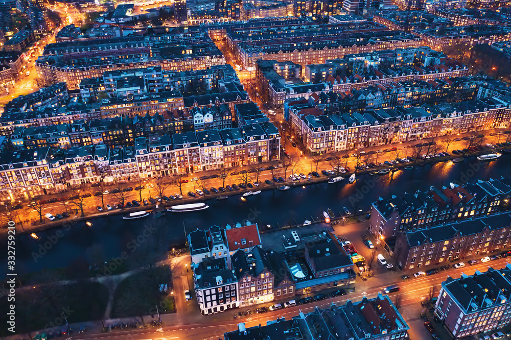 Amsterdam Netherlands aerial view at night. Old dancing houses, river Amstel, canals with bridges, old european city landscape from above.