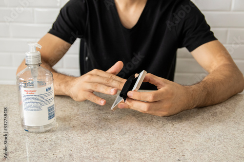 Coronavirus prevention. Man using alcohol gel to clean mobile smartphone. Hygiene concept. Novel coronavirus. (2019-nCoV). Covid-19. photo