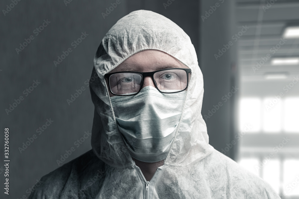 portrait of physician with protective suit and steamed up glasses which reflecting an empty corridor of hospital