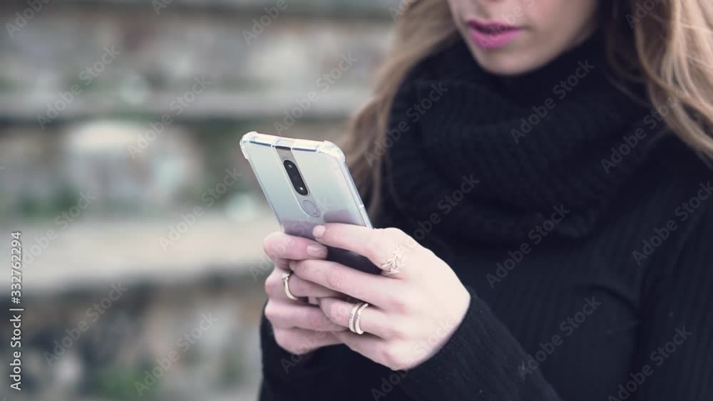 Slow motion shallow depth of field close up of a millennial girl texting and using social media on her smart cell phone at an outdoors park Slow motion shallow depth of field close up of a millennial girl texting and using social media on her smart cell phone at an outdoors park