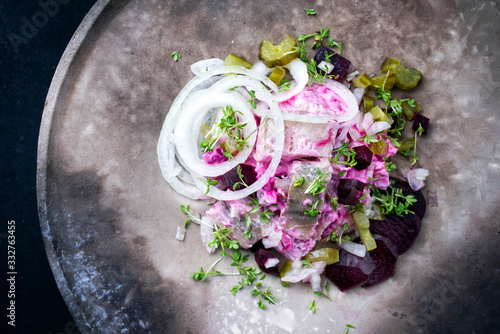 Traditional matie herring with beetroot salad and onion rings offered as top view on a rustic modern design plate with copy space left photo