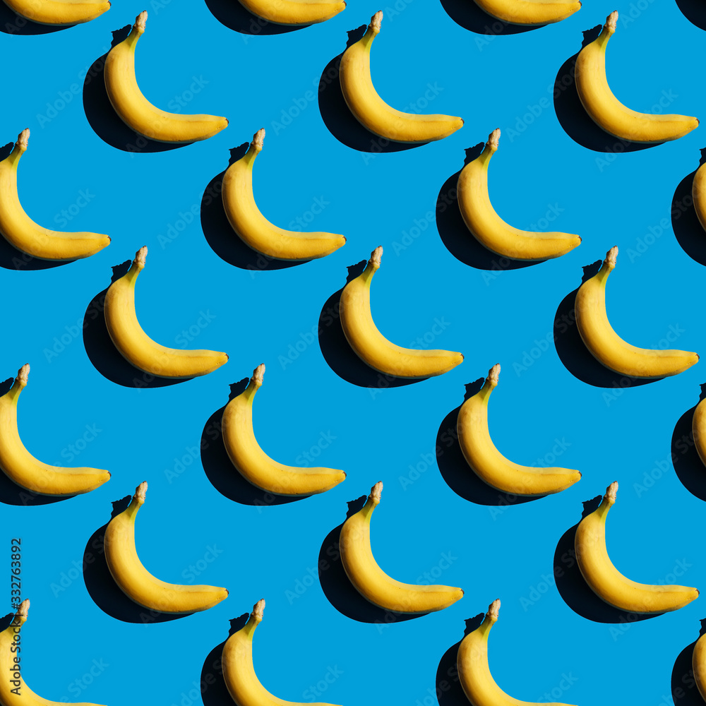 Seamless bananas pattern. Creative yellow food on blue background. Fresh season fruit texture with strong shadows