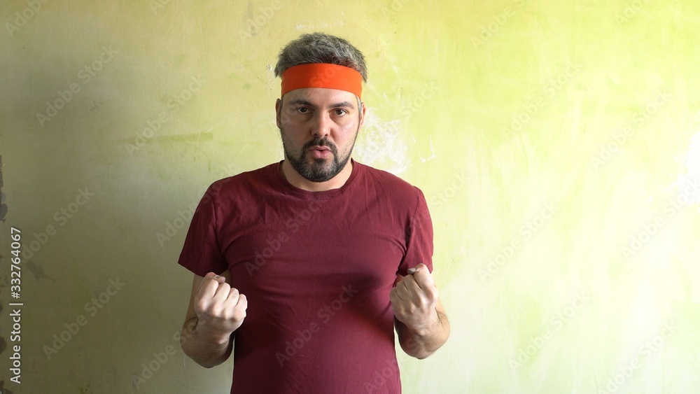 Fototapeta premium Bearded man against the wall. Good mood. Engaged in martial arts. Repair work in the room. Frick.