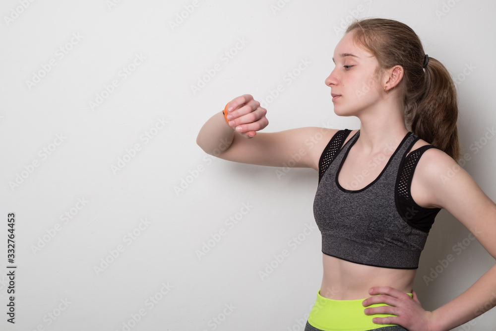Sports young girl with fitness bracelet for sports. Teen girl in sportswear looking at fitness bracelet. Sports girl in a topic for yoga. Sports young girl with fitness bracelet for sports. Teen girl in sportswear looking at fitness bracelet. Sports girl in a topic for yoga.