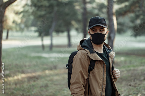 Young man in medical mask walking in park  © darakaliton