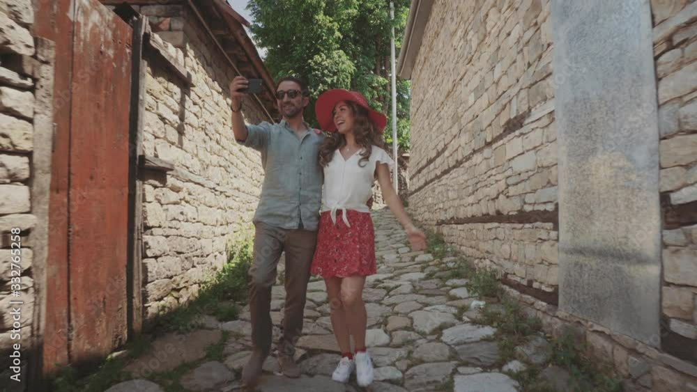 A pair of lovers in casual wear walk and take a selfie old street A pair of lovers in casual wear walk and take a selfie old street