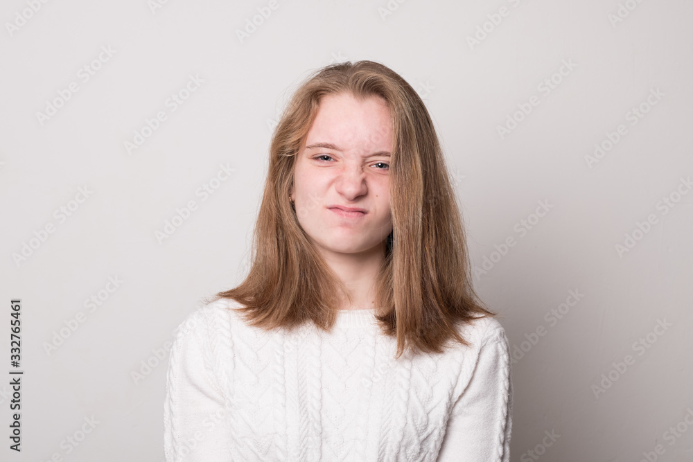 Emotional teen girl grimaces. Studio image of a cute smiling young girl on a gray background. Emotional teen girl grimaces. Studio image of a cute smiling young girl on a gray background.