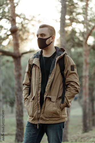 Wallpaper Mural medium shot portrait of man in medical mask. Adult person in black mask standing in park and looking sideways Torontodigital.ca