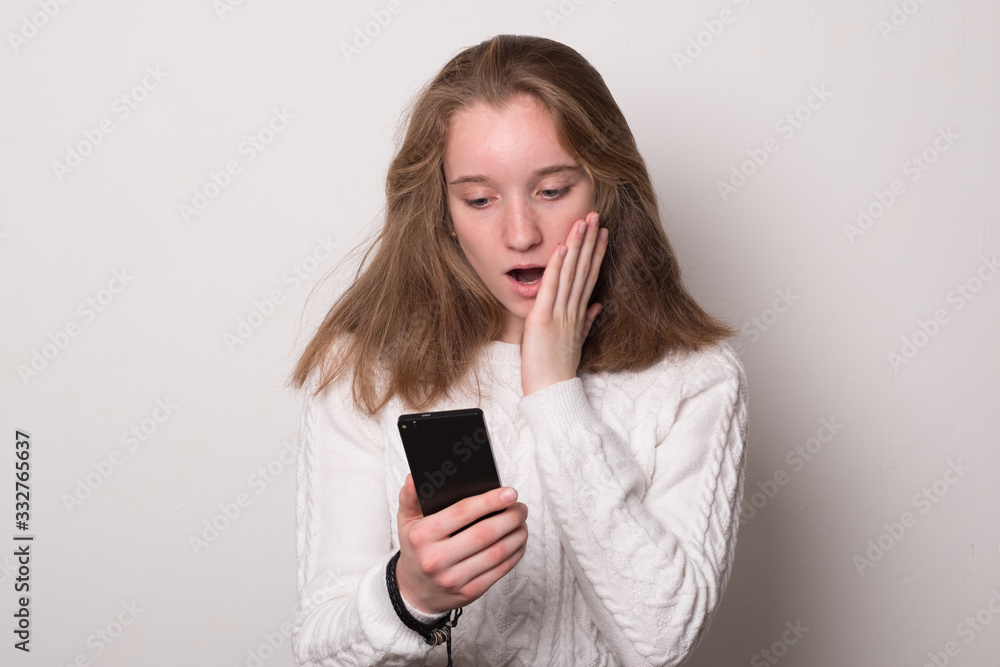 Cute girl holding a smartphone. Positive caucasian teen girl with smartphone. Cute girl holding a smartphone. Positive caucasian teen girl with smartphone.
