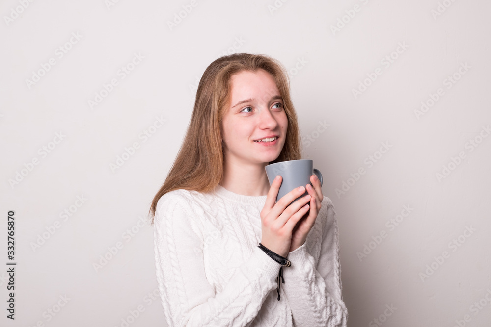 Positive girl holds a mug of tea. Teen girl drinks from a mug. Positive girl holds a mug of tea. Teen girl drinks from a mug.