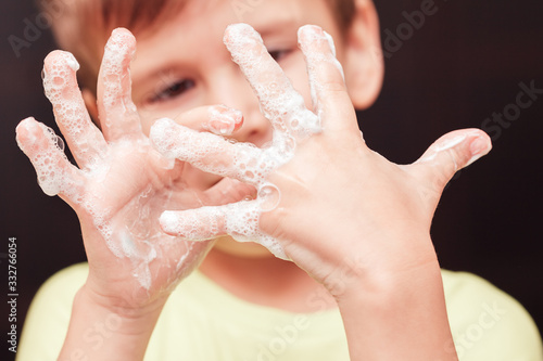 Cute boy looking at his hands with soupsuds, focus on hands