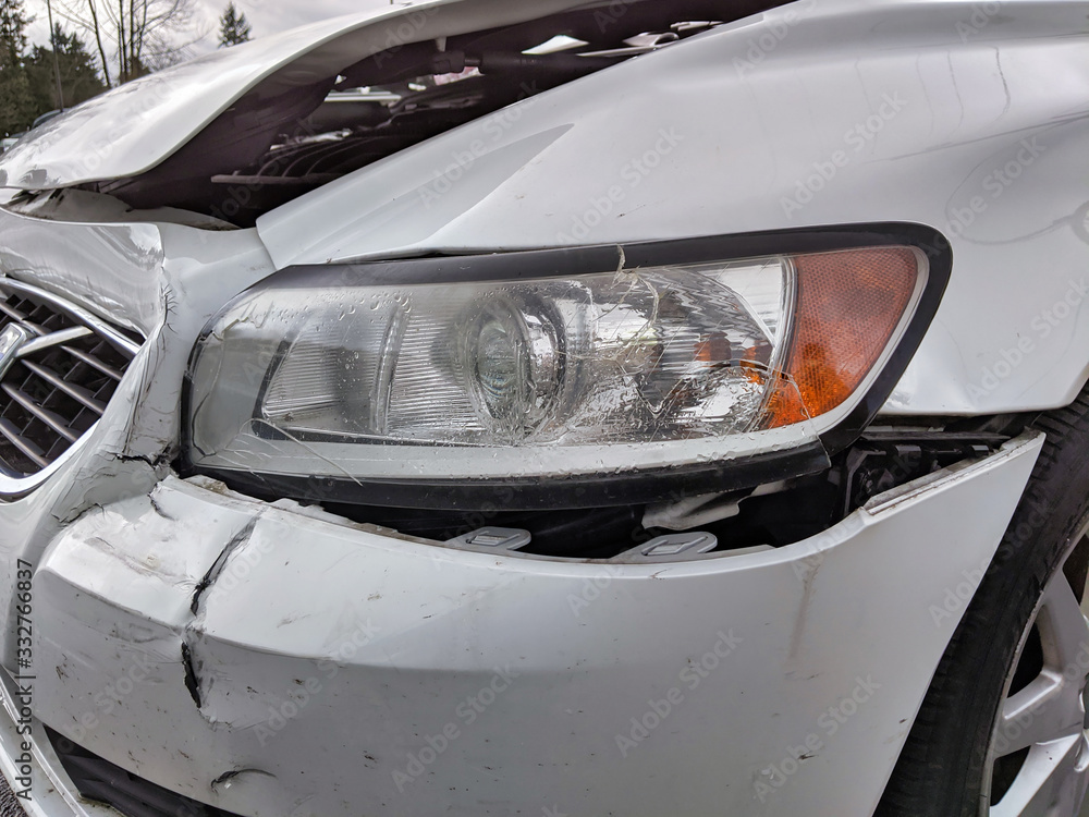 severe damage to the front bumper and headlight of a white car