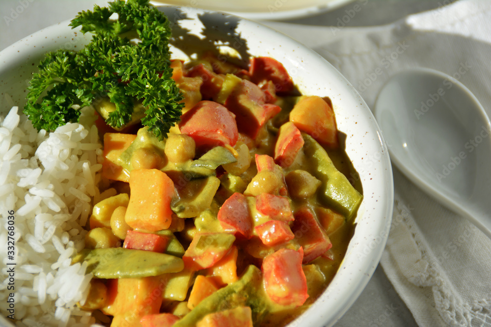 Veganes Süßkartoffel-Kichererbsen-Curry mit Zuckerschoten und Reis auf hellem Hintergrund
