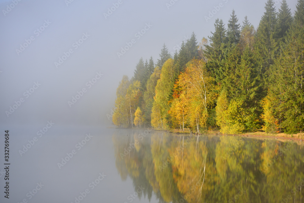 Autumn landscape in the mountains with trees reflecting in the water at St. Ana's lake, Romania Autumn landscape in the mountains with trees reflecting in the water at St. Ana's lake, Romania