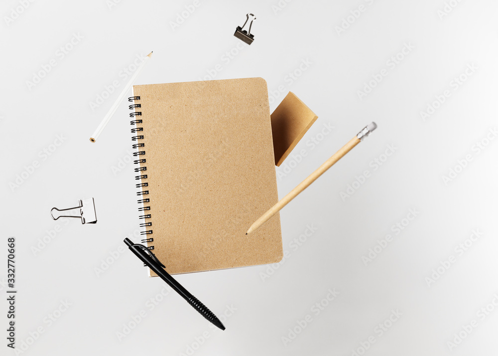 Stationery set. Levitation of notepad, pencils, pen, sticker and binder clips. Copy space on notebook and notes. Writing tools. Office supplies. Isolated on gray backdrop
