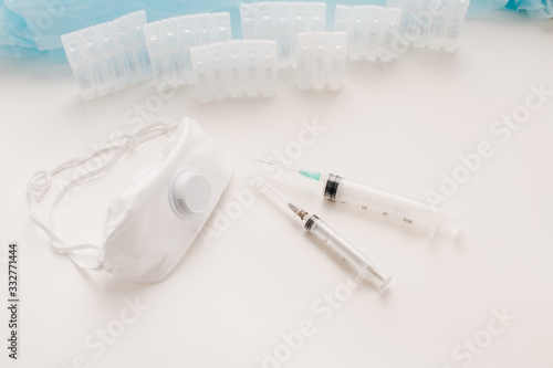 Medical ampoules with solution, syringes and protective mask respirator on the table