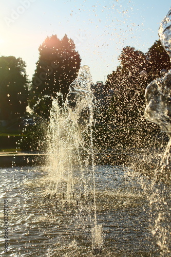 jet and spray of the fountain in the sun glare in the park