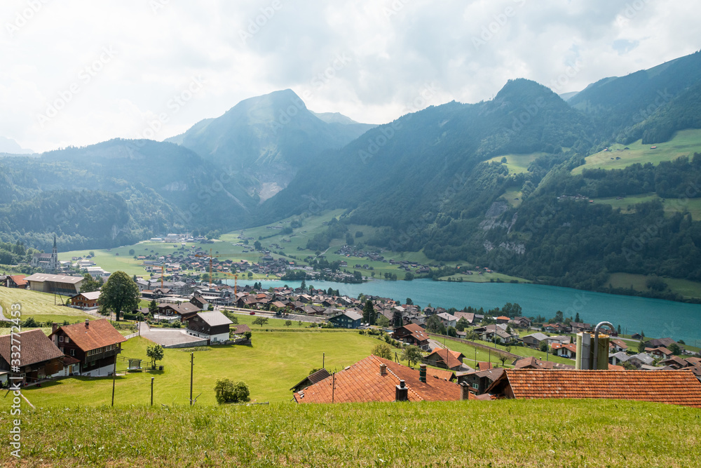 View of swiss village Lungern with traditional houses along the lake Lungerersee, canton of Obwalden, Switzerland. Incredibly bewitching and calm place.
