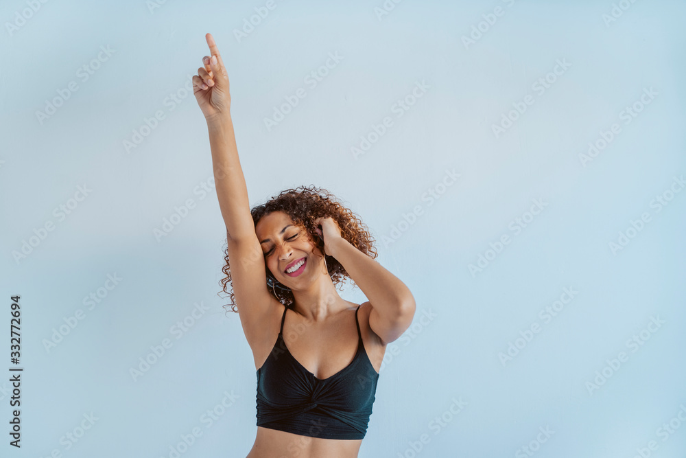 Young afro cheerful woman dancing to the beat and rhythm of black music. Afro culture lifestyle with technology at home. Fit african american dancer listening to music with wireless headphones. Young afro cheerful woman dancing to the beat and rhythm of black music. Afro culture lifestyle with technology at home. Fit african american dancer listening to music with wireless headphones.