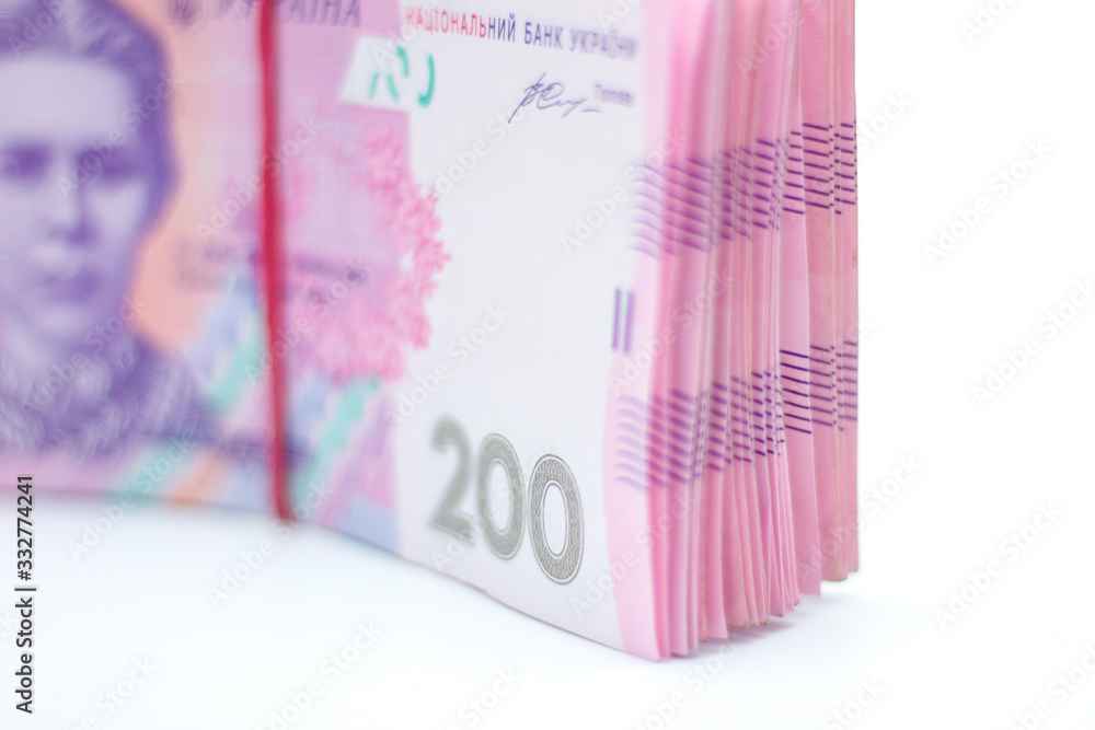 A lot of new banknotes in denominations of 200 Ukrainian hryvnias bandaged with an elastic band isolated on a white background with shadow. European money exchange. Ukraine currency. Selective focus A lot of new banknotes in denominations of 200 Ukrainian hryvnias bandaged with an elastic band isolated on a white background with shadow. European money exchange. Ukraine currency. Selective focus