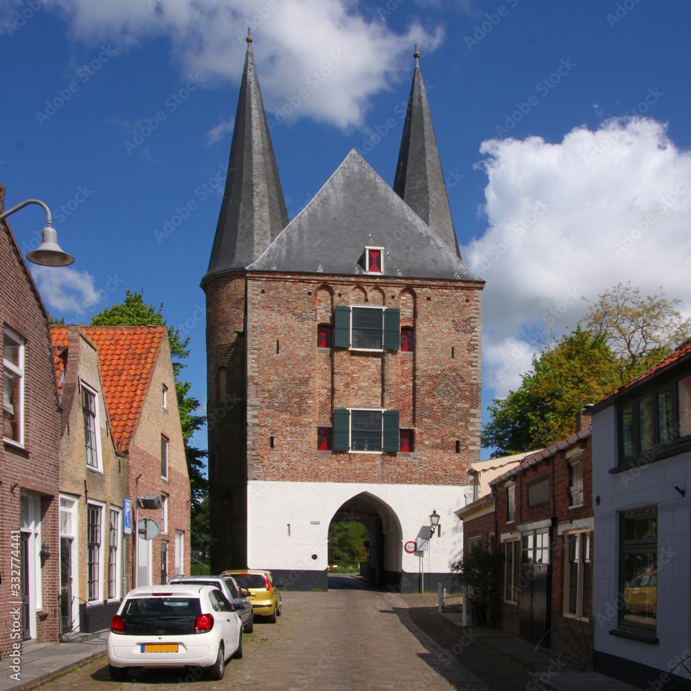 Obraz premium Gothic Nobelpoort city gate in Zierikzee at the end of a historical paved residential village street in the Netherlands