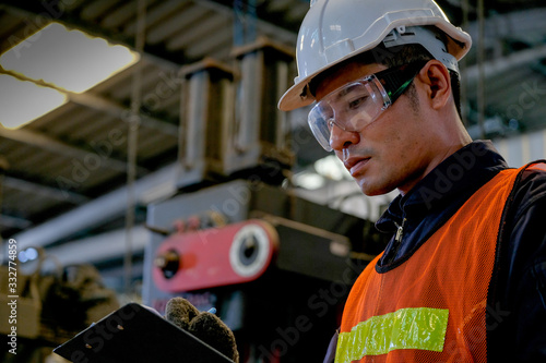 Canvastavla Close up Asian worker or technician man write on document paper in factory in front of machine
