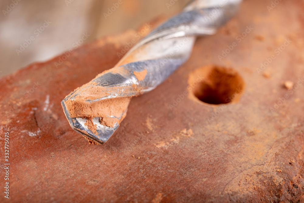 Drilling a hole in a clay brick. Carbide drill and red brick. Drilling a hole in a clay brick. Carbide drill and red brick.