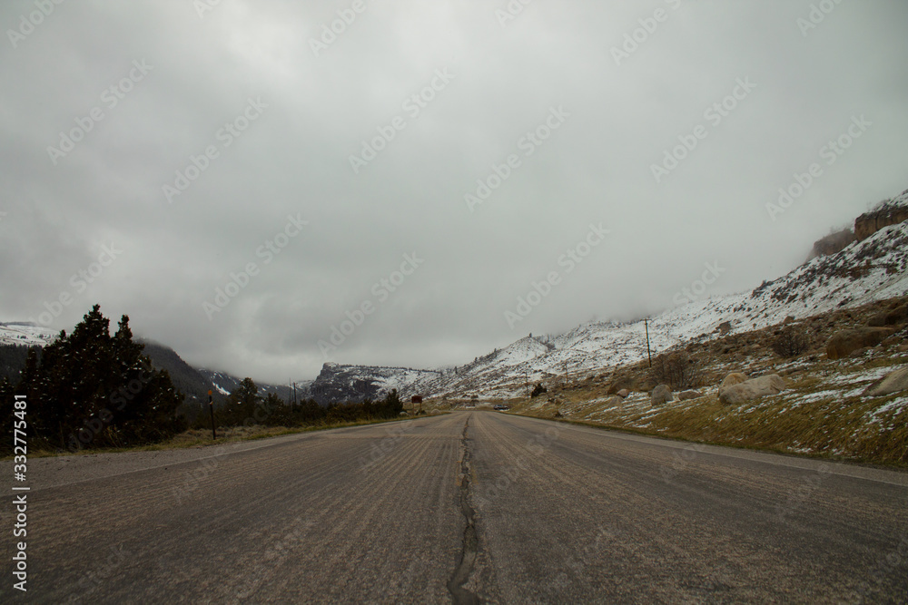 Fototapeta premium A lonely cold winter road leading towards snowy mountains in Wyoming