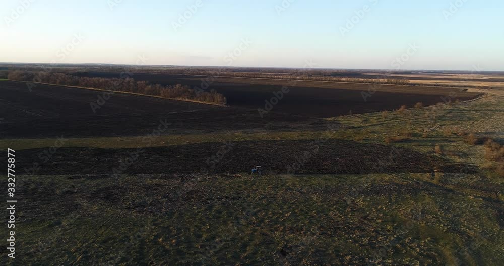 Blue tractor on the field seeding agriculture video from drone on the sunset.View from the high of the early spring Ukraine farm with tractor when the sun goes down.