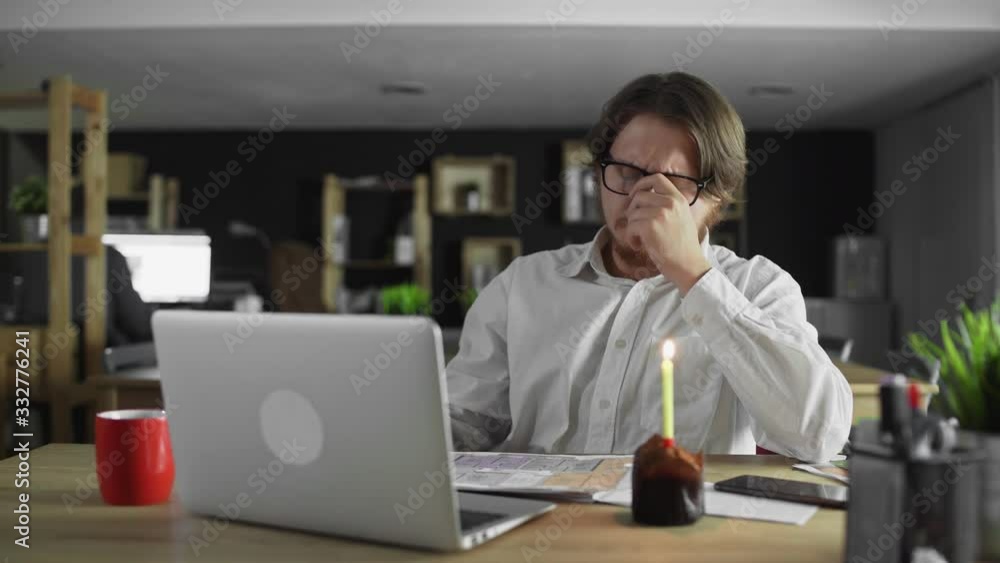 Sad and tired businessman celebrating a lonely birthday in the office Sad and tired businessman celebrating a lonely birthday in the office