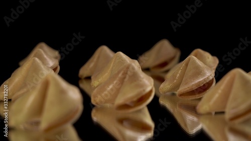 A lot of Chinese cookies rotate on a black background. Traditional fortune cookie. Nice view on spinning biscuit crispy sweet cookie.
