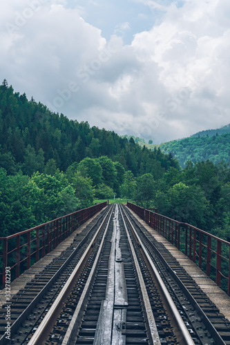 Railroad track on mountains background. Railway station on forest background.