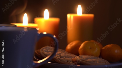 Nice holiday footage with focus on tea steam with candles, oranges and homemade cookies on the background.
